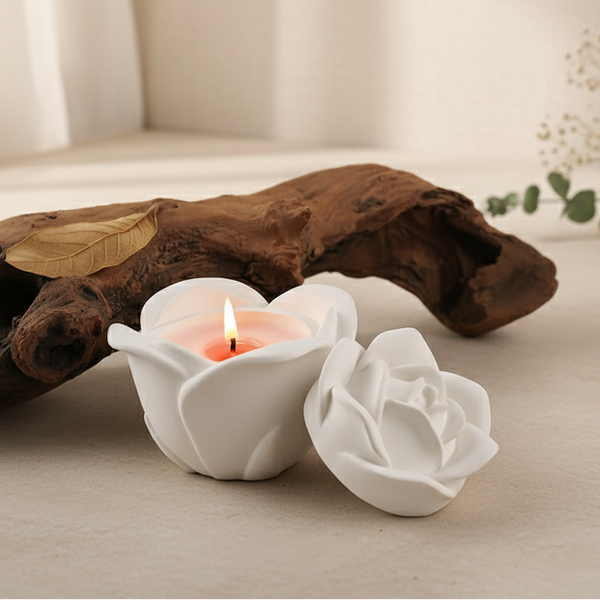 Pink rose-shaped candle holder with a lit candle on a dark surface