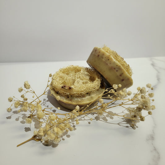 Two soaps with natural textures on a white background with dried flowers.