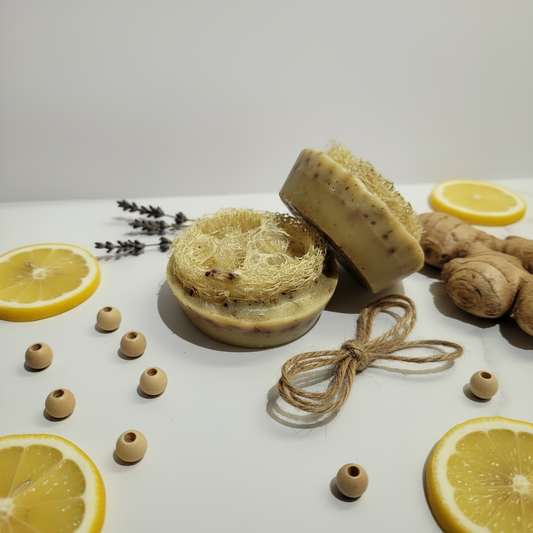 Three soaps with natural textures on a white surface with lemon slices and ginger.