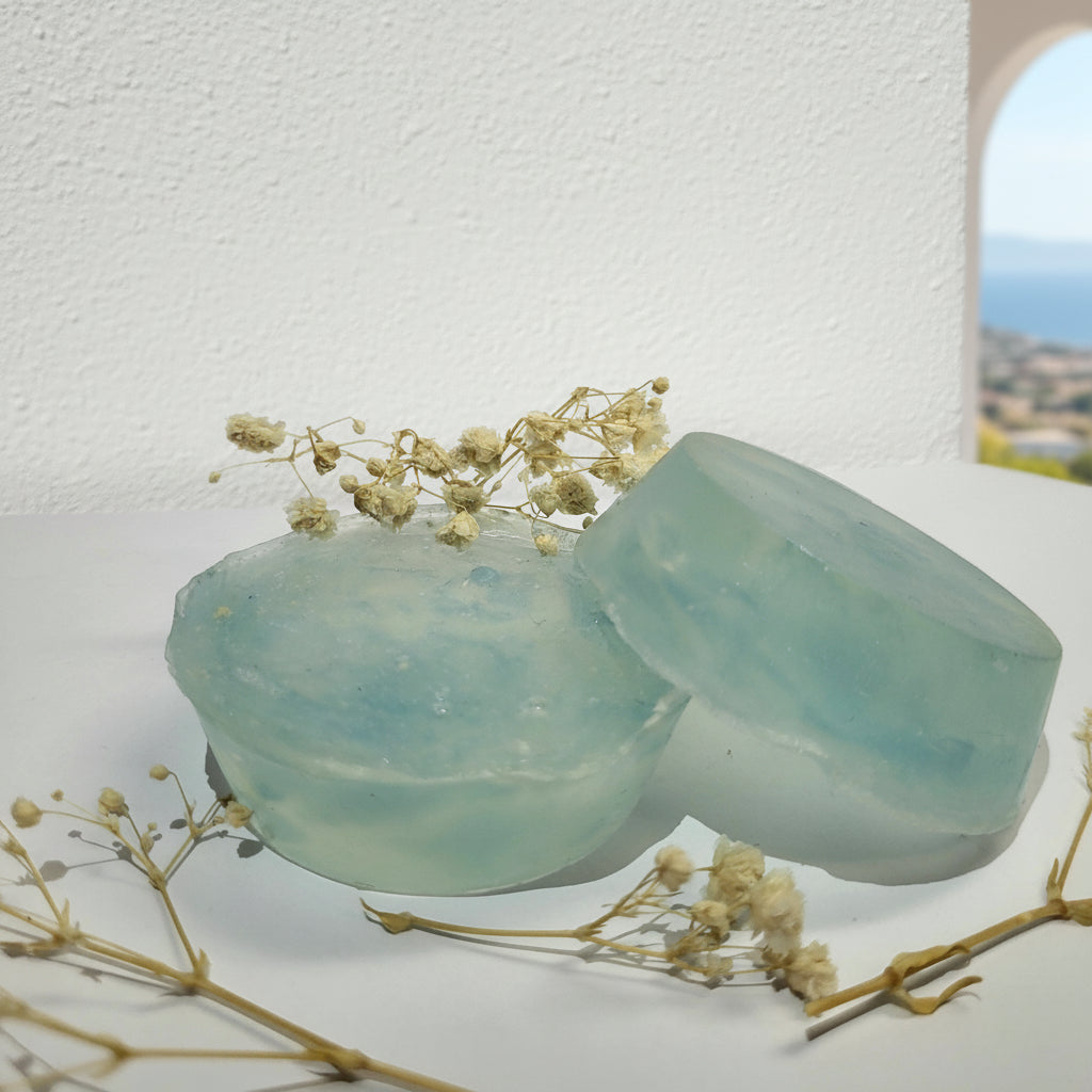 Two light blue soap bars with dried flowers on a white background