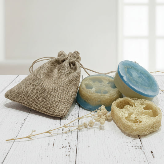 Two blue soaps with a natural loofah and a brown drawstring bag on a white background.
